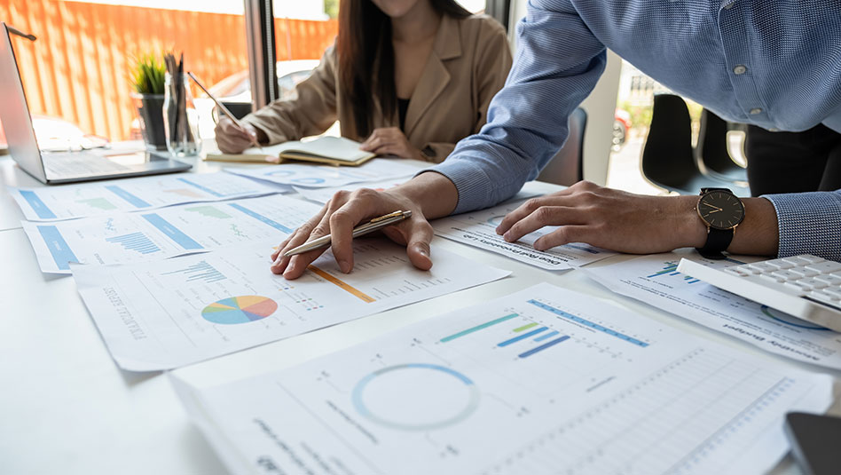 Man and woman scrutinizing printed charts on a table.