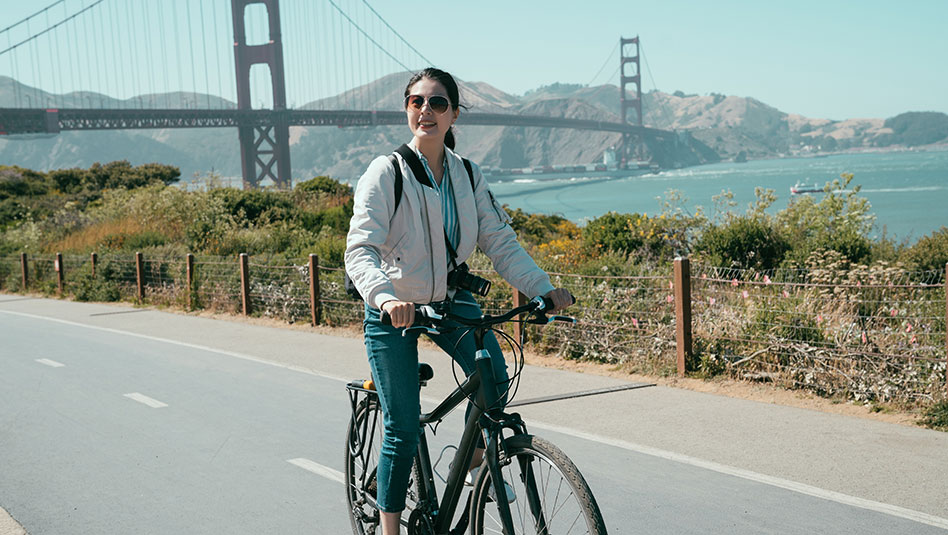 A person on a bicycle with a bridge in the background