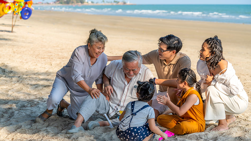 A grandfather and grandmother having fun with their children and grandchildren on the beach.