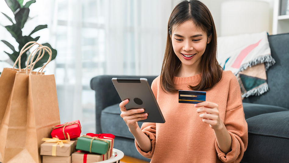 A person holding a credit card and tablet