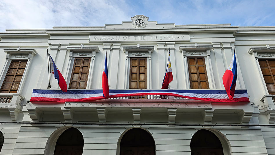 Front view of the Bureau of the Treasury with four Philippine flags.