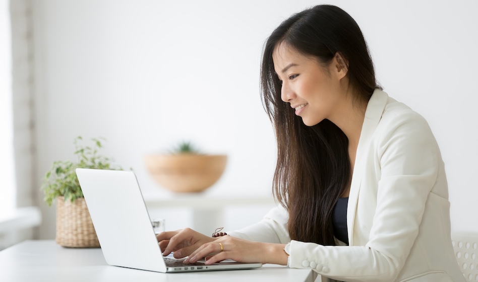 Smiling young asian businesswoman using computer working online