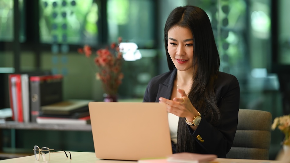 Asian woman investor working ,reading business data on laptop computer while sitting in modern workplace